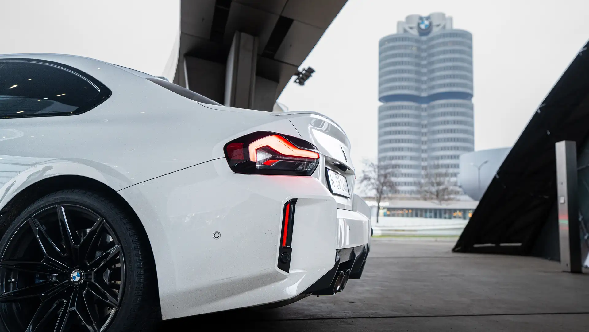 Weißer BMW M2 vor der BMW Welt mit dem markanten zylinderförmigen BMW Gebäude im Hintergrund